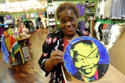 Objets à l’effigie de Mandela présentés le 5 février 2010 dans une boutique de Johannesbourg Le visage du premier président noir d’Afrique du Sud sourit sur des T-shirts, des drapeaux, des badges qui parsèment les étals judicieusement positionn