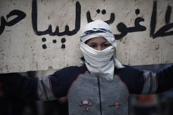 UN JEUNE MANIFESTANT, LE VISAGE À DEMI VOILÉ, BRANDIT UNE AFFICHE CONTRE LE «TYRAN DE LA LIBYE», LORS D'UNE DÉMONSTRATION CONTRE LE COLONEL KADHAFI, À DERNA. UN JEUNE MANIFESTANT, LE VISAGE À DEMI VOILÉ, BRANDIT UNE AFFICHE CONTRE LE «TYRAN DE LA LIBYE», LORS D'UNE DÉMONSTRATION CONTRE LE COLONEL KADHAFI, À DERNA.